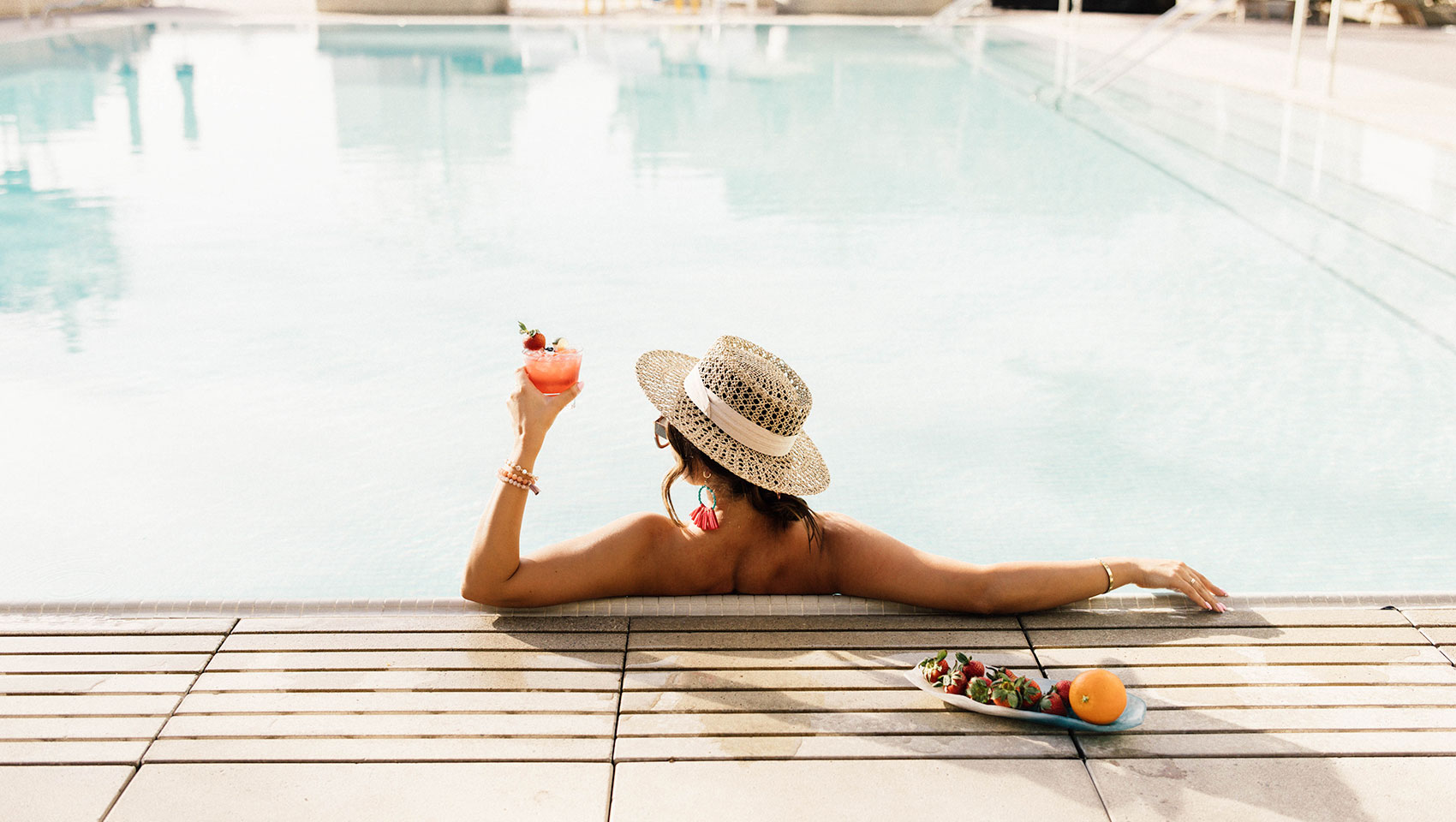 woman in pool with cocktail
