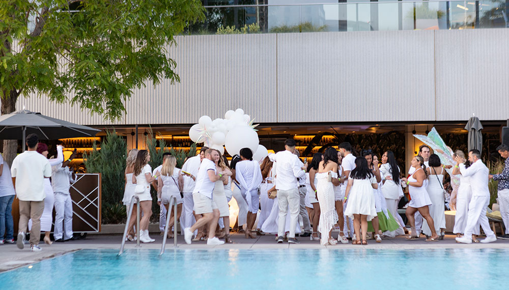 Party goers dressed in white by pool
