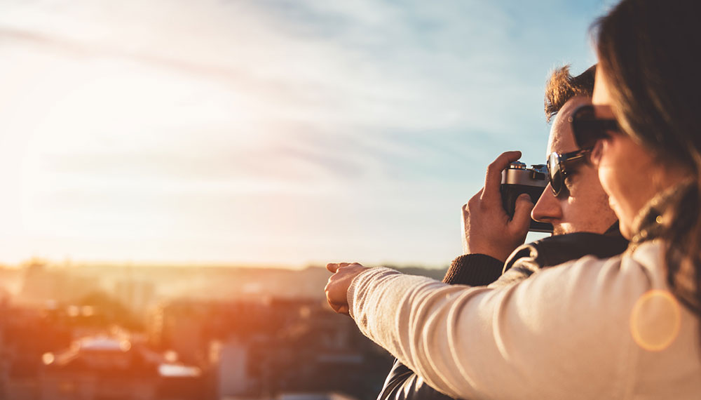 A man and woman looking out over a city taking a picture