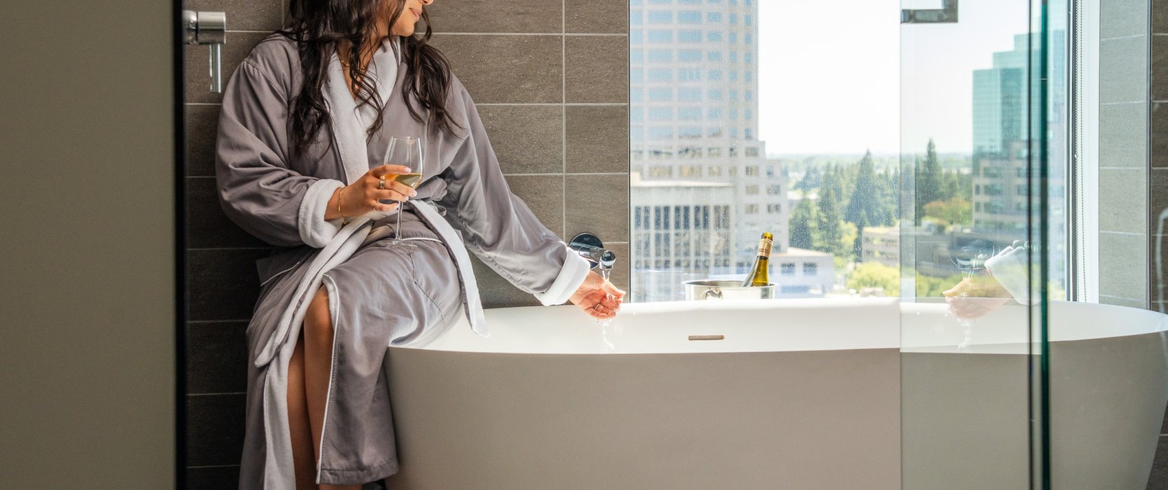 Guest relaxing by bathtub with city views at Kimpton Sawyer Hotel